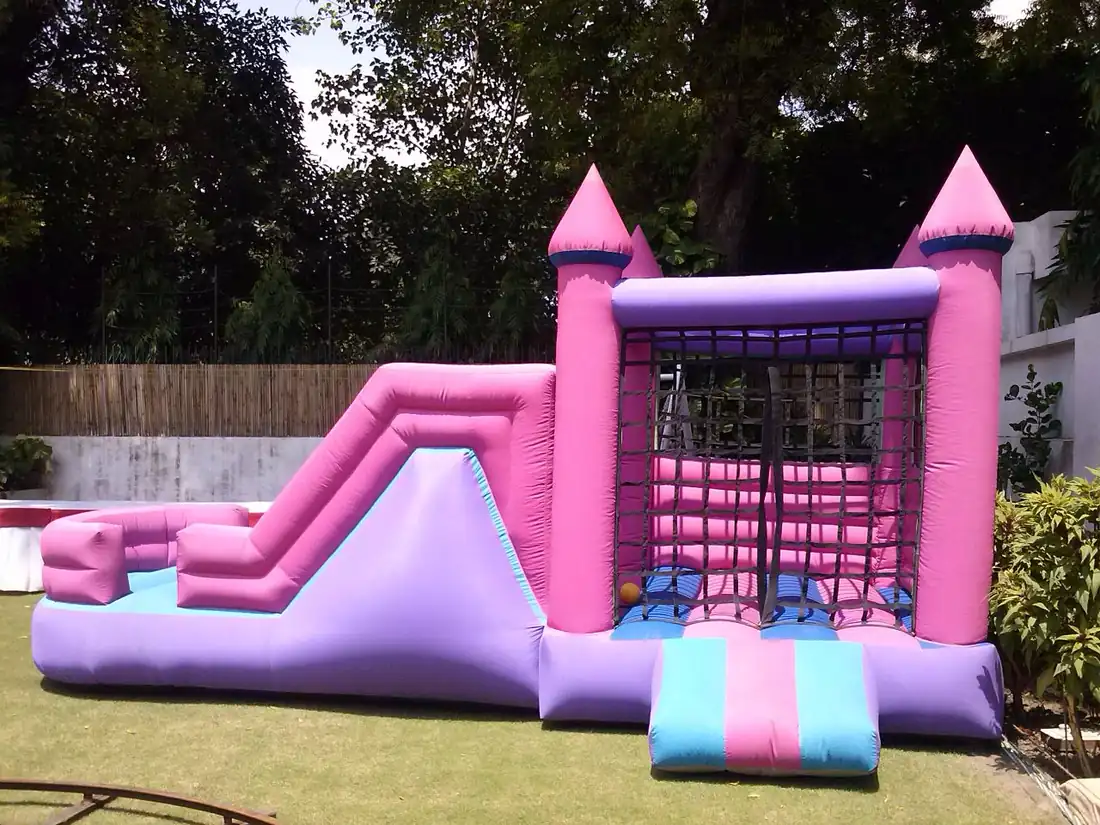 Pink and purple bouncy castle with slide set up on a lawn